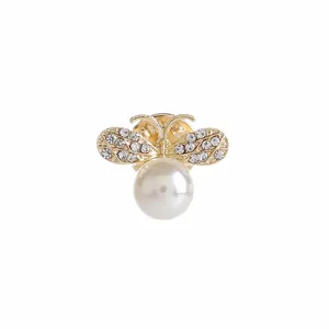 Detalle de un broche de abeja dorada con alas de strass y una gran perla blanca redonda