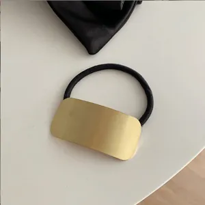 Detail van de gouden geborstelde metalen plaat op een zwart elastisch haarelastiek