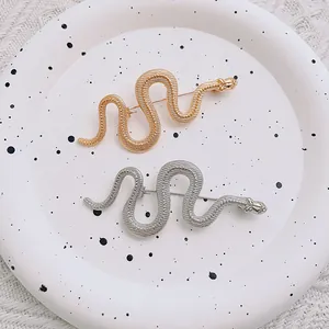 Spille a serpente minimaliste in oro e argento con trama metallica su vassoio in ceramica
