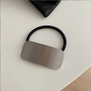 Detailopname van een vierkante geborstelde metalen gesp op een zwart elastisch haarelastiekje
