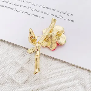 Elegant floral rhinestone brooch with a gold-tone safety pin backing on white fabric