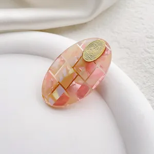 Primer plano de pinza de acetato con textura de mármol rosa y detalle de metal dorado