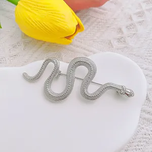 Spilla a forma di serpente argento con scaglie su vassoio bianco e tulipani gialli