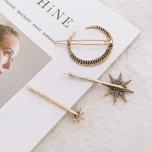 Vintage gouden haarspeldjesset met maan en sterren en strass op een wit tijdschrift