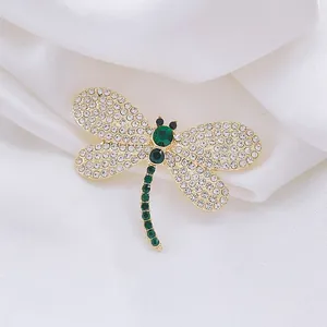 Élégante broche libellule émeraude avec strass blancs étincelants sur des ailes dorées