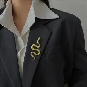 Dettaglio di una spilla a serpente dorata con trama a scaglie su un risvolto grigio