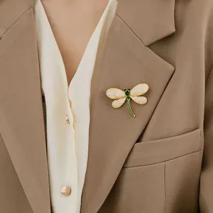 Élégante broche libellule émeraude avec cristaux sur le revers d'un blazer camel chic