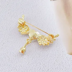 Vue arrière de la broche ailes d'ange dorées avec pendentif goutte sur tissu rose