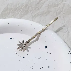 Gedetailleerde macro-opname van een goudkleurige haarspeld met strass op wit aardewerk