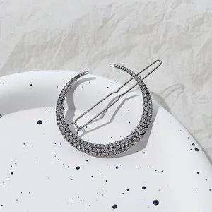 Detail van zilveren maan haarclip met fonkelende steentjes op een wit bord gepresenteerd