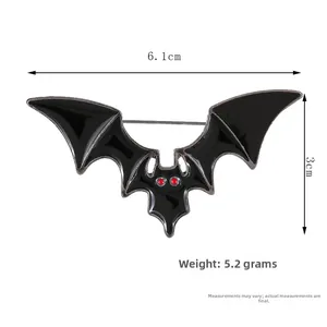 Detailed view of black bat wing brooch with red eye beads showing 6.1cm width dimensions