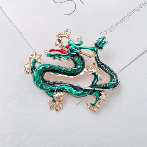 Detailed view of an ornate Chinese dragon brooch featuring emerald green enamel on gold