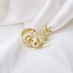 Golden snowflake and ginkgo leaf brooch with pearls on white silk background
