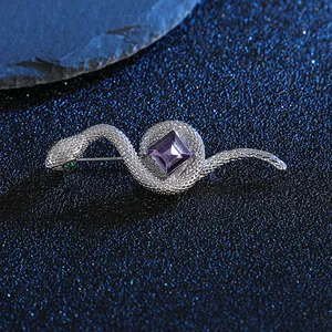 Silberne Schlangenbrosche mit lila quadratischem Edelstein und grünen Augen auf Blau