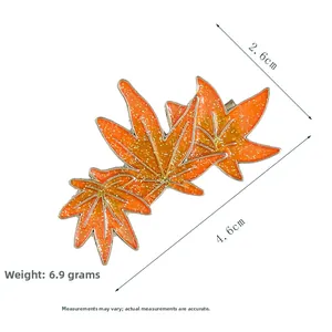 Close-up of orange maple leaf hair clip with glitter finish and pearl detailing