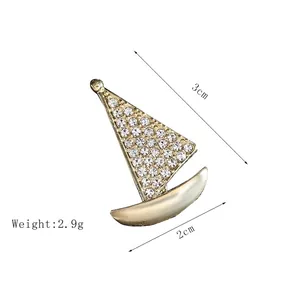 Dettaglio spilla a forma di barca a vela dorata con dimensioni 3x2cm e strass