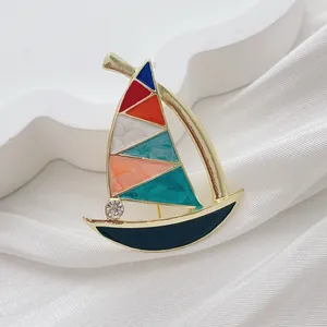 Macro detail of enamel sailboat brooch with colorful sails and sparkling rhinestone