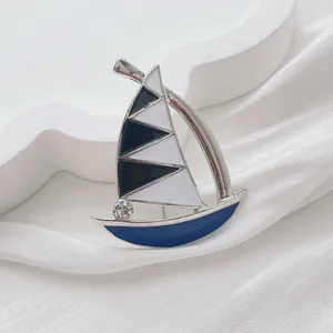 Detail of enamel sailboat brooch with black and white sails and sparkling crystal accent