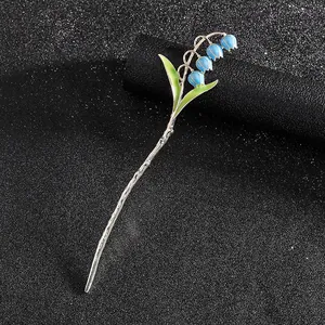 Eleganter Maiglöckchen-Haarstab mit blauen Emaille-Blüten und grünen Blättern auf Schwarz