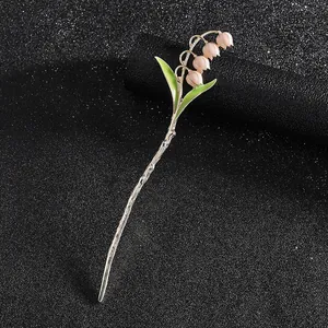 Silberne Maiglöckchen-Haarnadel mit rosa Blüten und grünen Blättern auf schwarzem Grund