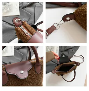 Detail view of brown fuzzy dumpling bag showing metal zippers and soft teddy plush texture