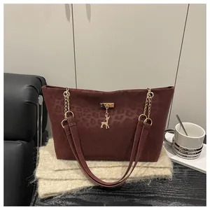 Dettaglio della borsa shopper rosso vino con stampa leopardata e ciondolo a forma di cervo