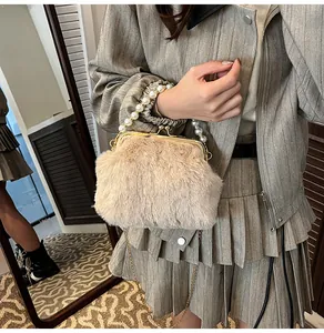 Detail van zachte faux fur crossbody tas met parelhandvat en gouden metalen sluiting