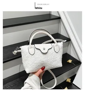 Detail of white plush dumpling bag with leather handle on minimalist stairs