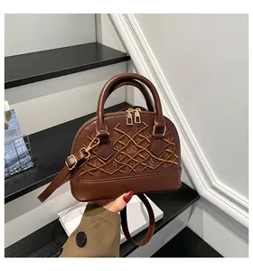 Detailaufnahmen der Stickerei und des Kronenlogos auf der dunkelbraunen Shell-Tasche