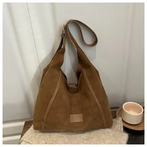 Close-up of brown suede hobo bag with adjustable strap in a warm autumn setting