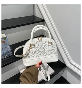 Detailansicht der weißen Muschel-Tasche mit strukturierter Stickerei und Goldbeschlägen