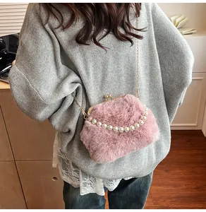 Detail van roze tas van imitatiebont met parelhandvat en gouden ketting op het model