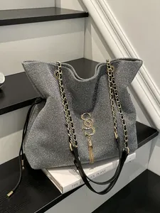 Silberne Glitzer-Einkaufstasche mit goldenem SS-Logo und Kettenriemen auf modernem Grund