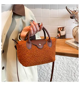 Detail of orange teddy plush handbag featuring brown leather handles and silver snap closure