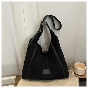 Detail of black faux-suede tote bag with matte finish on a soft knit sweater