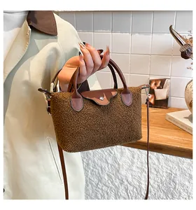 Detail of brown plush faux fur handbag with leather handle and silver button closure