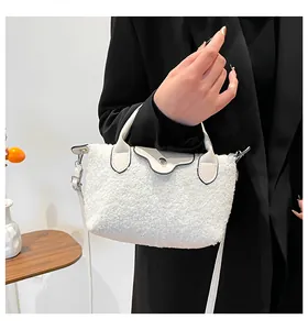 Detail of white faux shearling dumpling bag with black trim and long shoulder strap