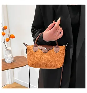 Detail of orange faux shearling bag featuring brown leather flap and metal snap button