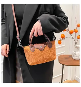 Orange plush dumpling bag with leather trim held by a model in a black winter coat