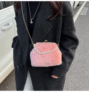 Detail van roze pluche crossbodytas met parelhandvat en gouden kettingriem op de jas