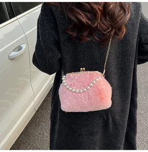 Roze pluchen crossbodytas met parelhandvat en gouden kettingriem in buitenopname