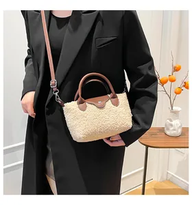 Detail of a plush beige faux fur handbag with brown leather flap and adjustable strap