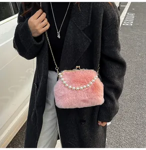 Roze tas van faux bont met parelhandvat en gouden ketting gedragen op een zwarte jas