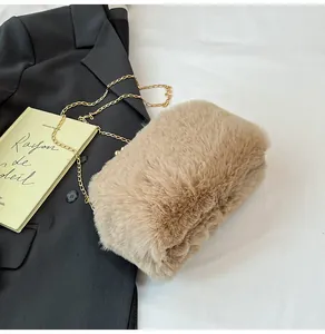 Detail van lichtbruine pluche crossbodytas met gouden ketting en parelsluiting op boek