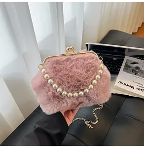 Detail van roze pluche crossbodytas met parelhandvat en gouden ketting voor dames