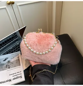 Detail van roze pluchen crossbodytas met parelhandvat en gouden ketting op bureau