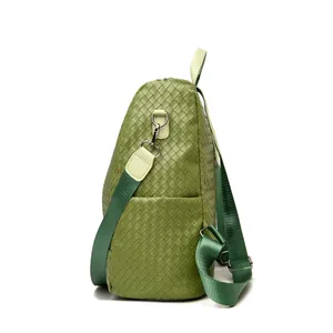 Detail showing olive green woven leather texture and metal strap hook on the backpack