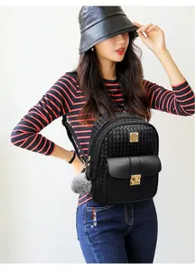 Detail of black woven texture backpack with gold buckle closure and grey pompom charm