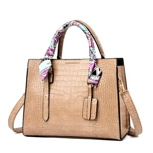 Detailed macro view of beige faux leather handbag with embossed stone texture and silk scarf
