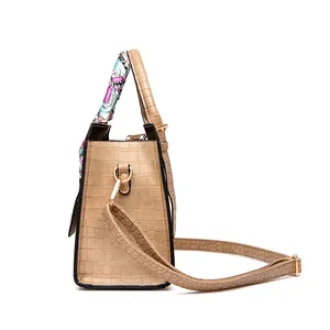 Side view of beige embossed crocodile handbag with decorative silk scarf and gold hardware